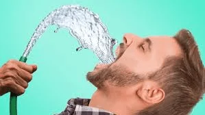 A man drinking from a water hose