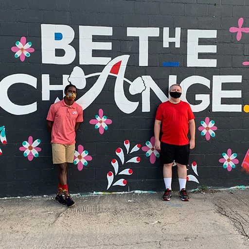 client highlight and trainer posing in front of an Austin Simply Fit mural