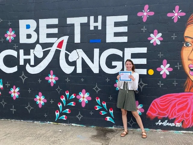 Scholarship recipient in front of mural