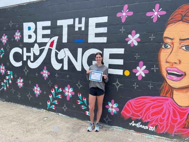 Scholarship recipient in front of mural