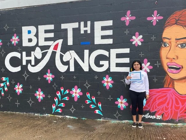 Scholarship recipient in front of mural