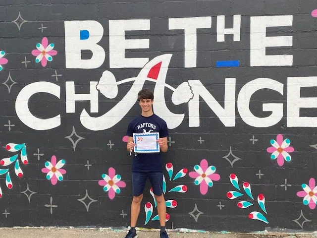 Scholarship recipient in front of mural