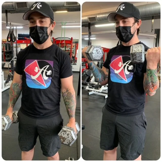 man with tattoo holding dumbbells