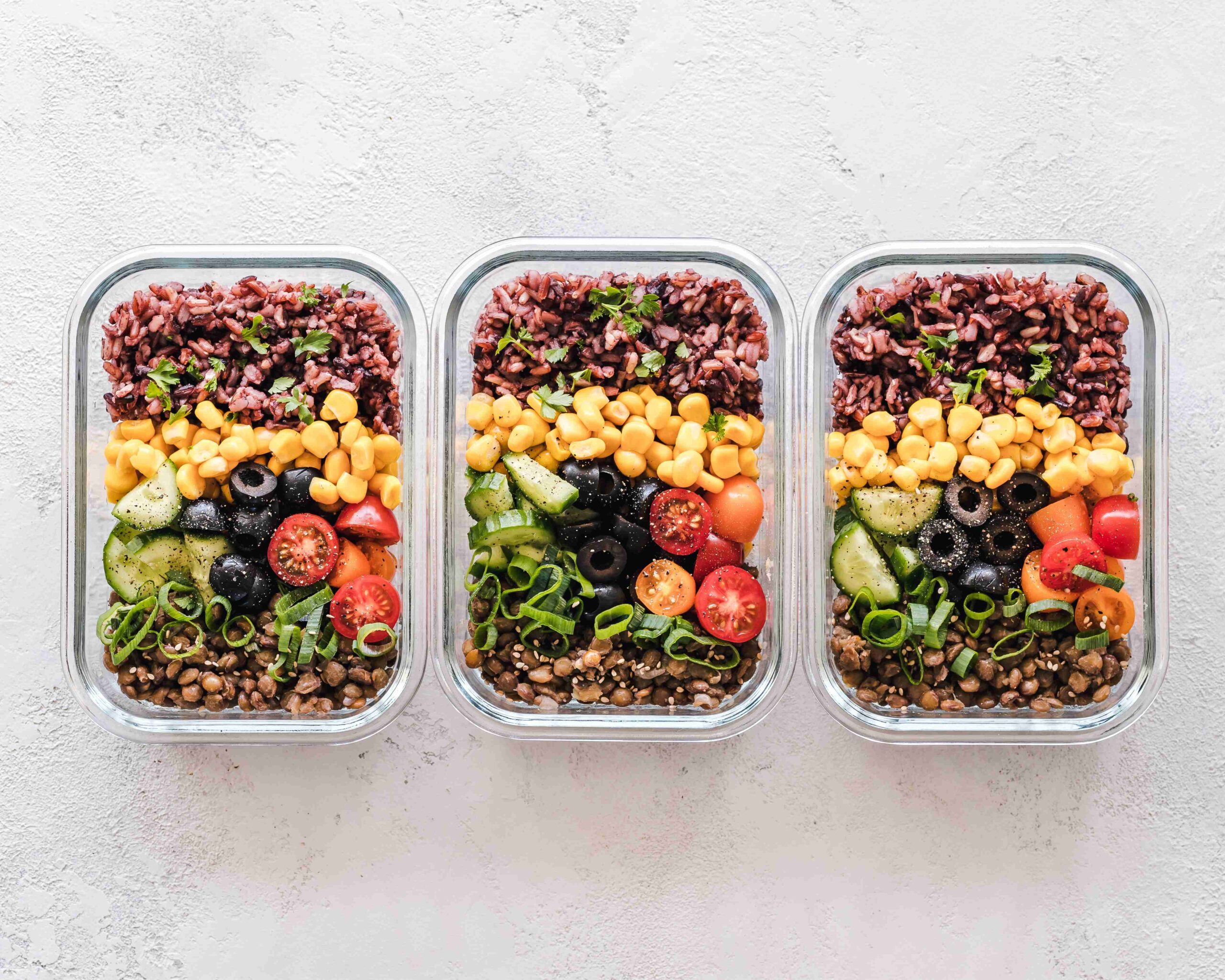 Three meal containers with beans and fresh vegetables