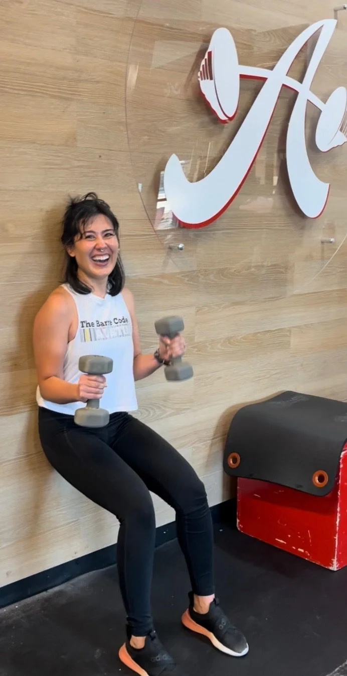 Client doing a wall sit with dumbbells