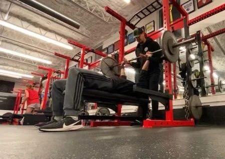 Person doing a bench press with a spotter