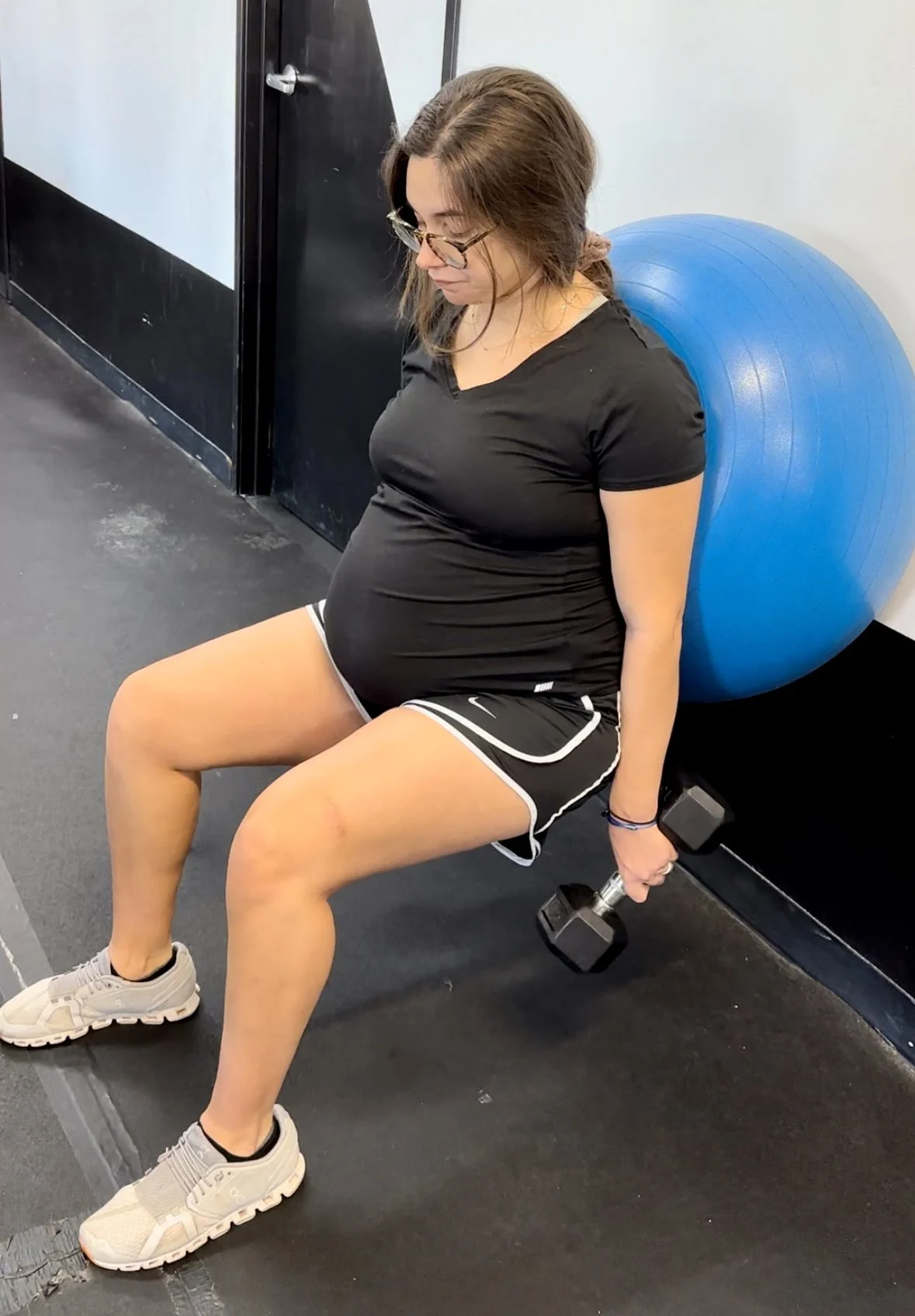 person doing a squat with an exercise ball and dumbbells