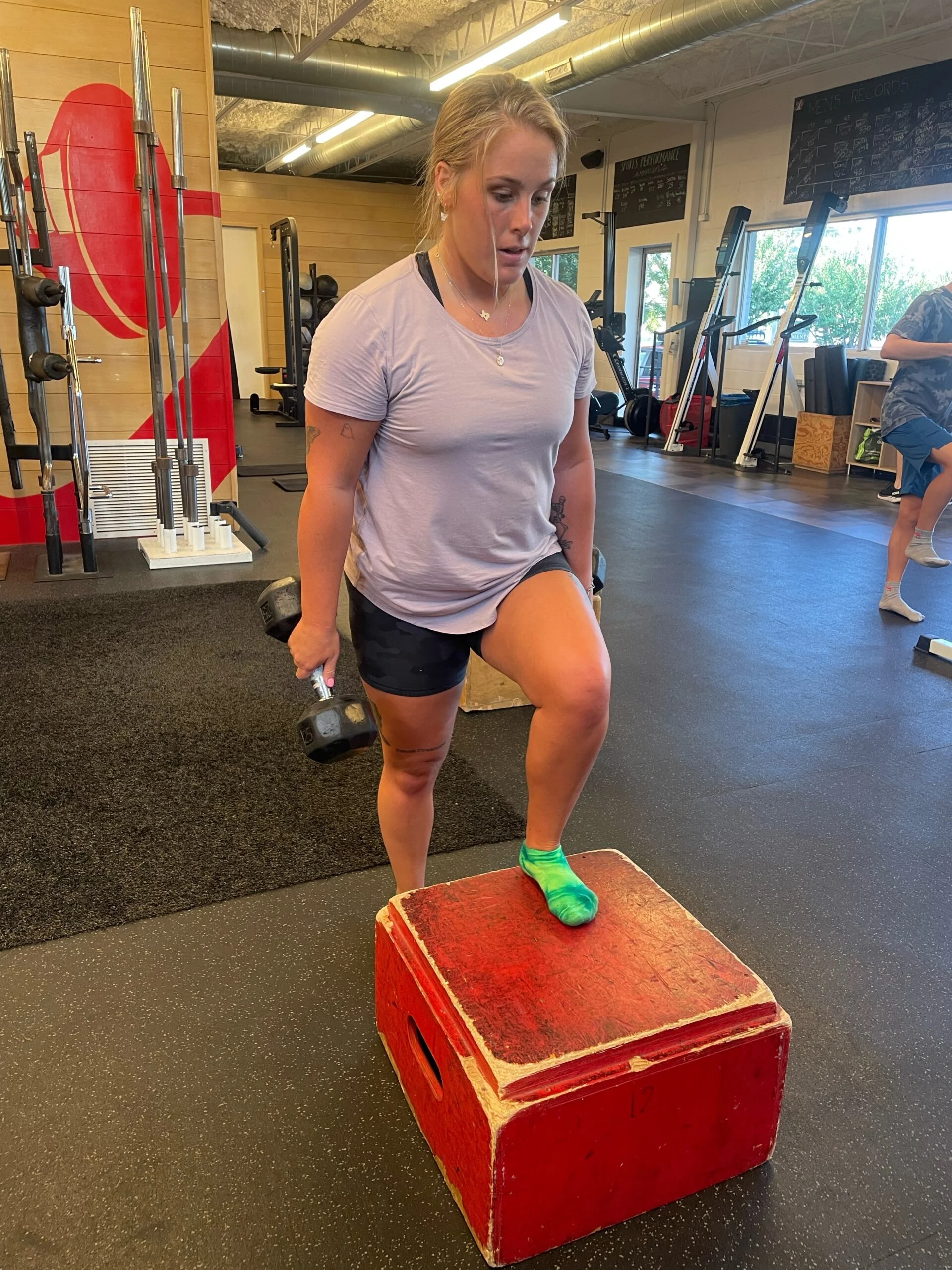Sports Performance client doing a step up with dumbbells