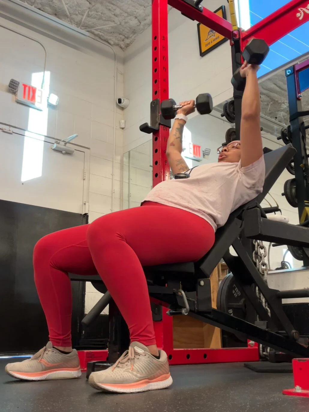Personal trainer Kimi Adeigbe performing an incline bench press
