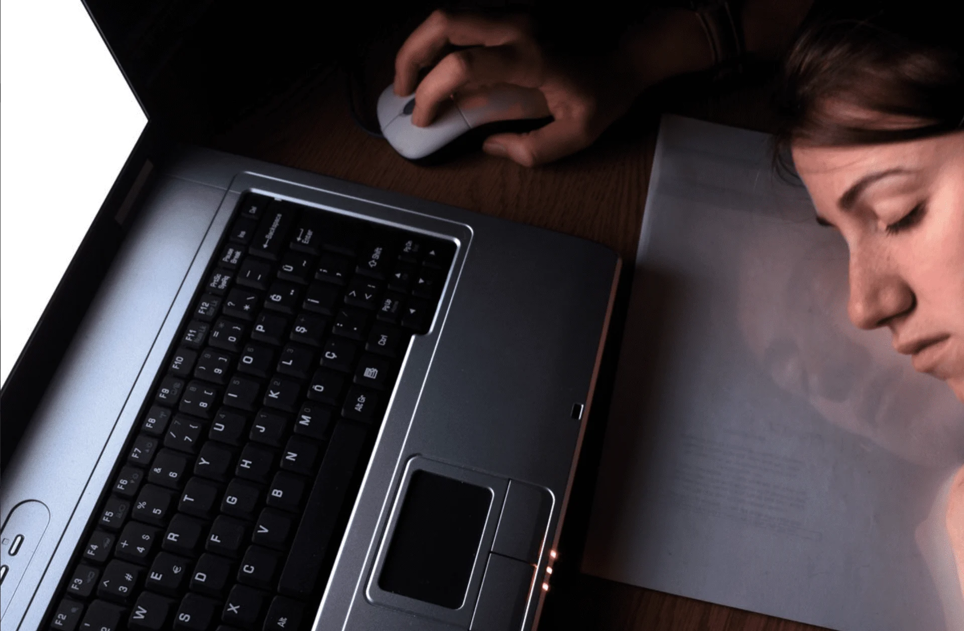 A person asleep in front of a laptop