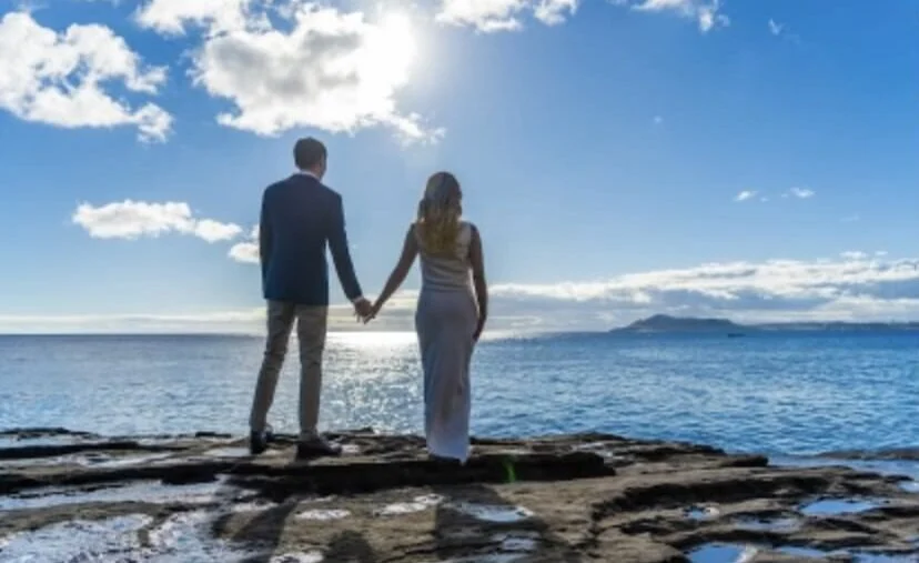 A bride and groom looking out over water
