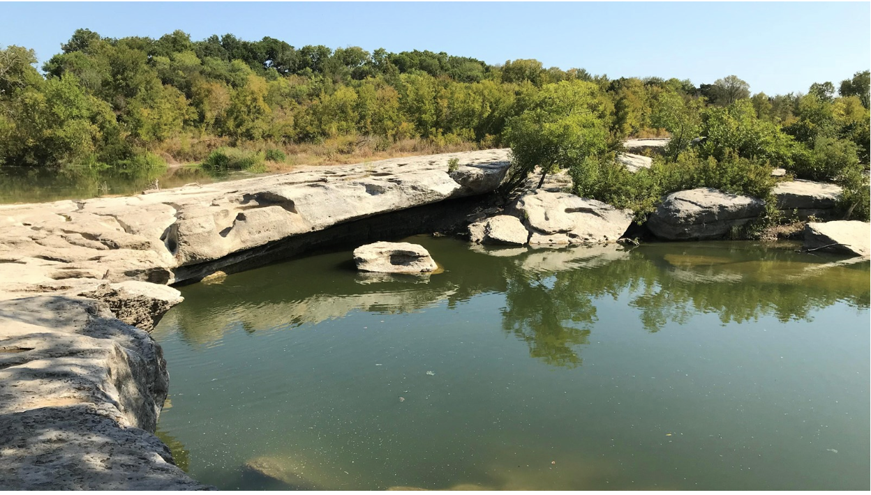 Image of McKinney Falls and trees under blue skies