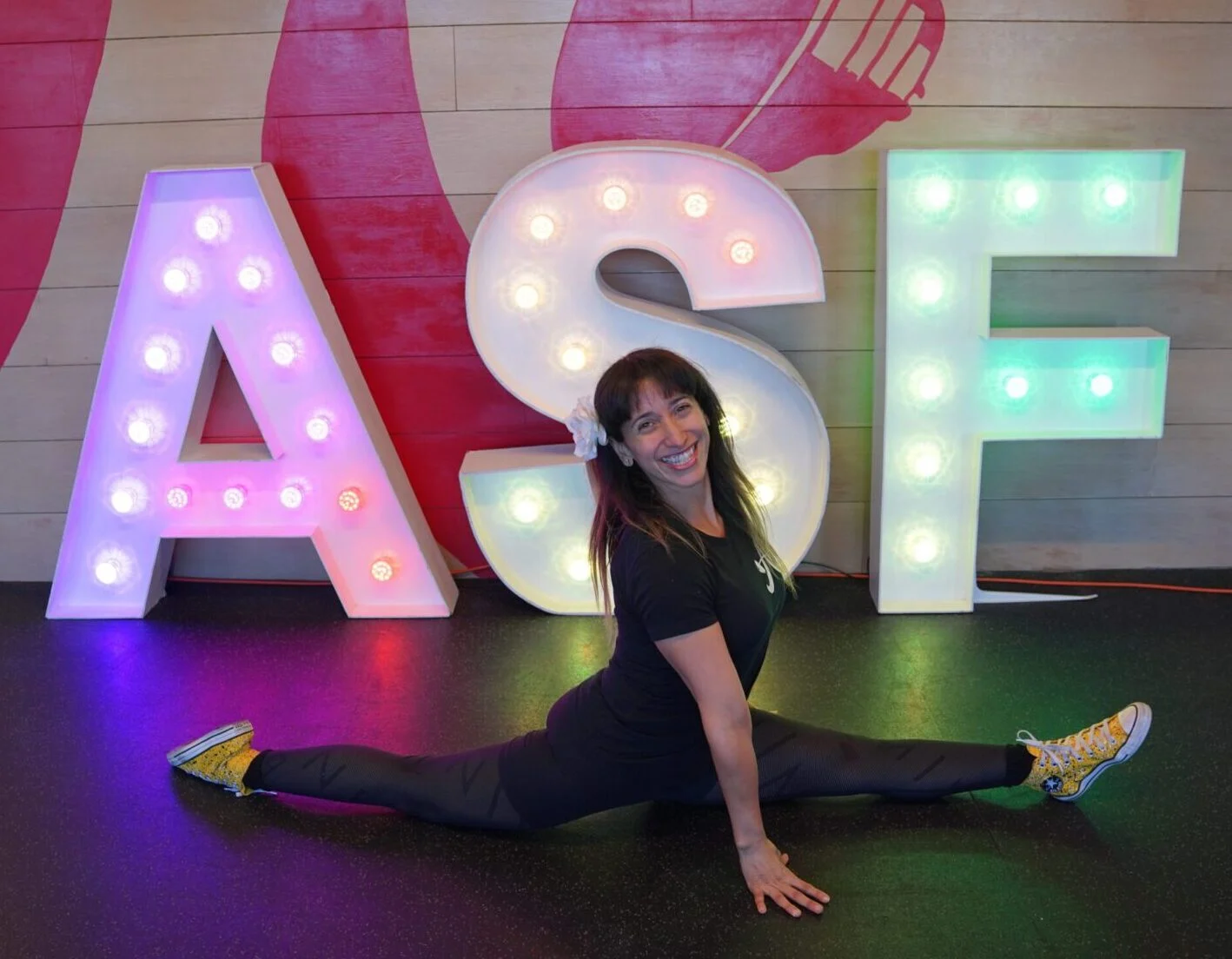 Personal trainer Vilita Cruz doing a split in front of an ASF marquee