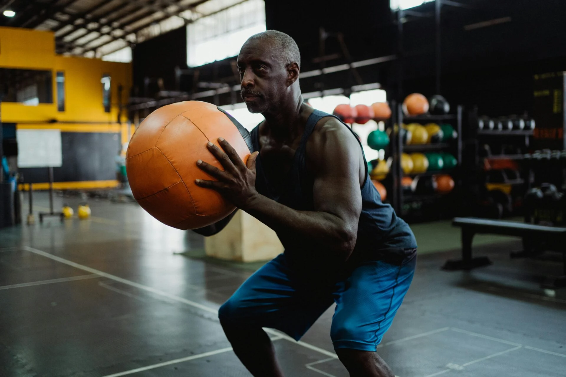 Older man performing a squat with a medicine ball. 