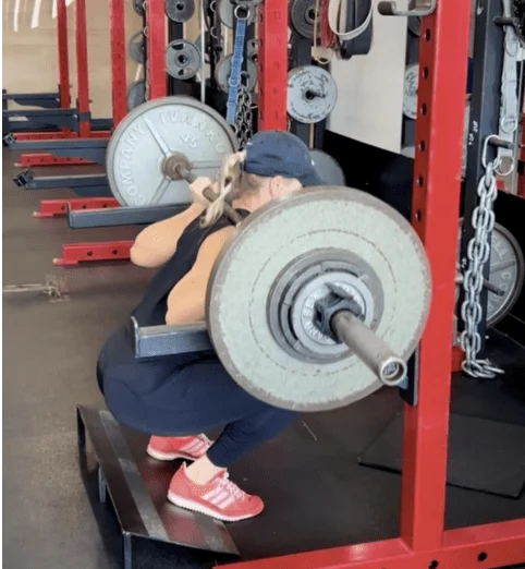 Trainer Krista Bergeron performs a barbell back squat on a slant board with full range of motion