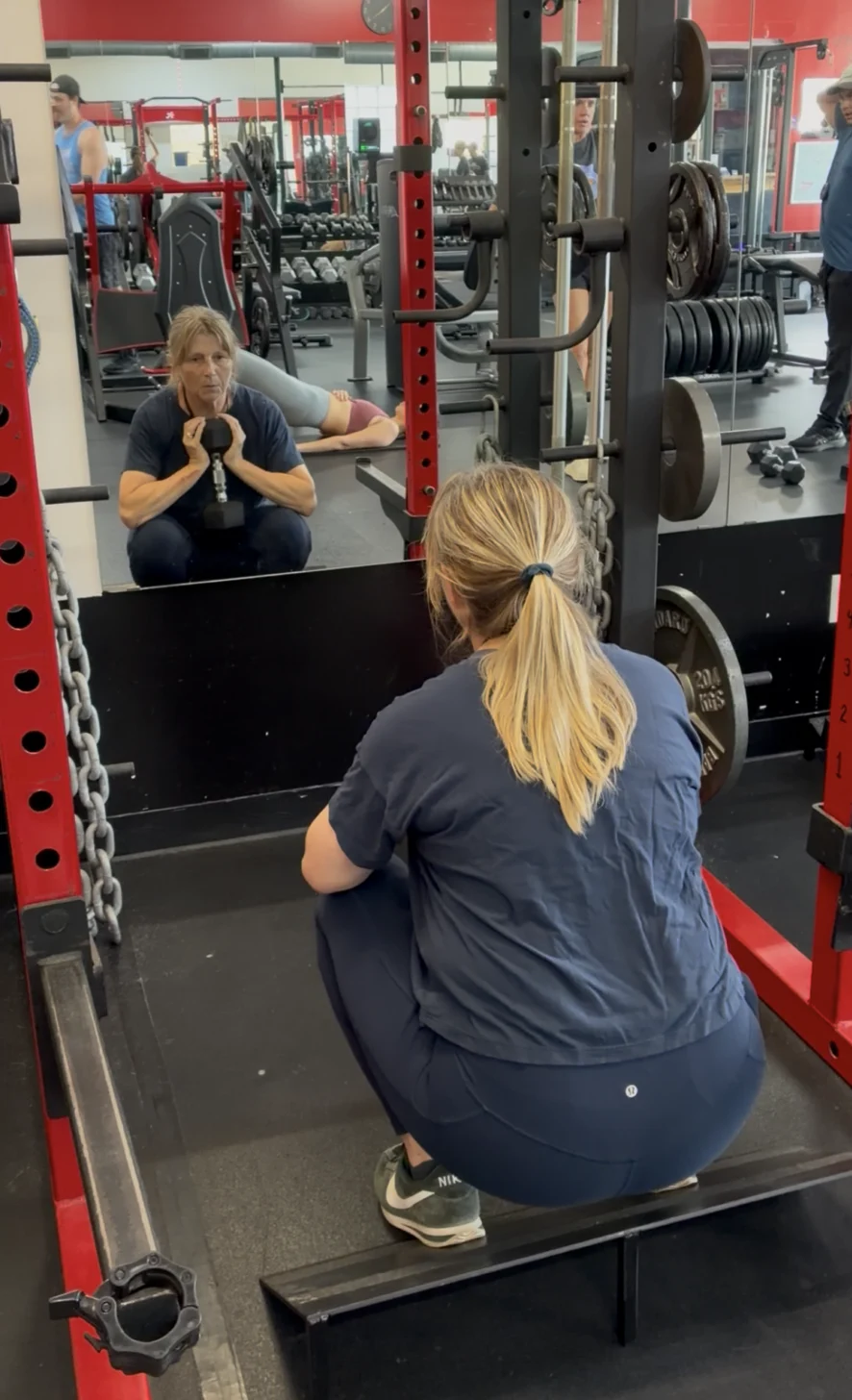 Active senior client doing goblet squat on slant board during weightlifting for seniors training